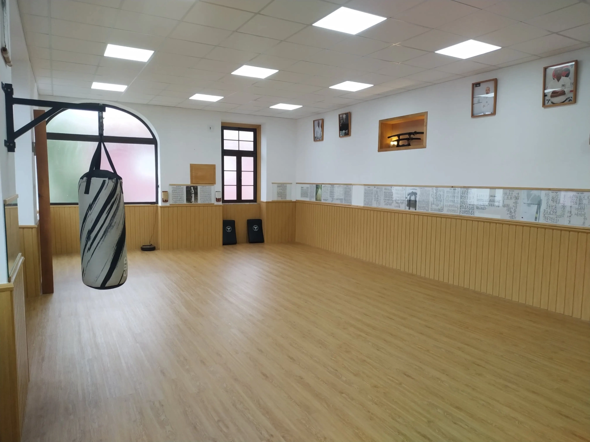 Sala de treino do dojo do Clube de Karaté Alcanena, com saco de pancada e fotografias na parede